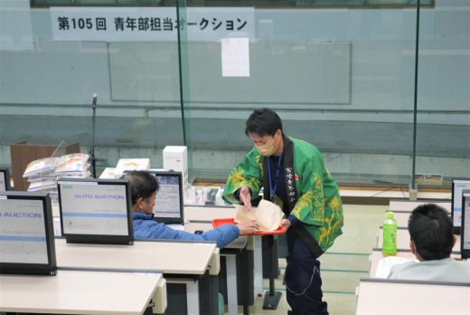 皆本青年部会長がセリ会場を回り、あんまんと肉まんを会員に振舞った