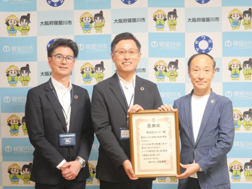 寝屋川市役所で寄贈式（左から）田中則行営業室長、笹井会場長、広瀬市長