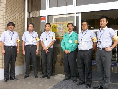 着用確認ポスターと腕章をつけたスタッフ