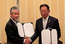 協同契約書を手に握手を交わす小林理事長（左）と新井代表理事（右）