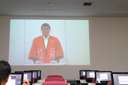 久野社長のあいさつが東京会場からオンライン中継された