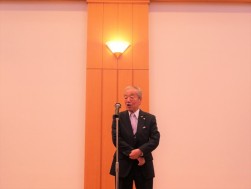 懇親会であいさつに立つ松本相談役