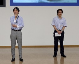 ＵＳＳ－Ｒ開設８周年記念ＡＡで挨拶に立つ瀬田大社長（写真左）と新美幸夫ゼネラルマネージャー