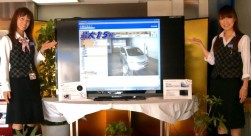 大抽選会の目玉賞品（アクオス６０型テレビ）を紹介するスタッフ。左：福井さん 右：勝野さん