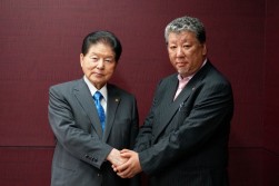 握手を交わす小川逸樹会長・最高経営責任者と鷹林康裕取締役社長