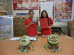 当日の賞品（オリジナルバインダーと甘納豆）を紹介するスタッフ