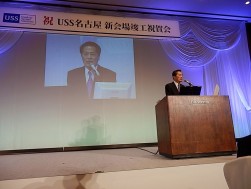 挨拶に立つ安藤之弘会長兼社長　スライドを使って新会場の新しい施設が紹介された。