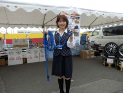 自動車部品販売会の模様　特に人気の高かった伸縮性の高いホースを紹介する三枡マネージャー