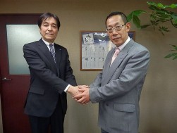 今後の協力を誓って握手する２人（左から羽田社長、塩原社長）