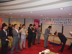 トップセールスコンテストの受賞者に深々と頭を下げる大川金融委員長