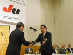 役員永年表彰を受ける松永会長・理事長（プレゼンターは宮谷英志副会長・副理事長）