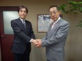 今後の協力を誓って握手する２人（左から羽田社長、塩原社長）