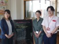女性事務局員が笑顔で会員を迎える（左から事務局の正木綾子さんと吉元紀子さん、黒木流通委員長）